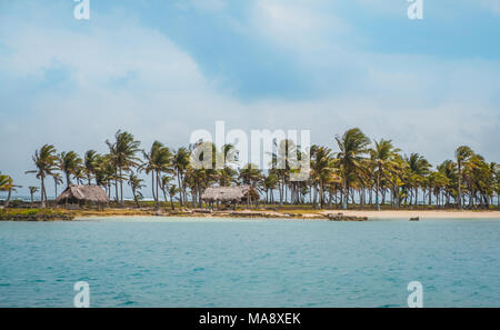 Wunderschöne Insel Strand mit Palmen und strohgedeckten Hütten an der Küste Stockfoto