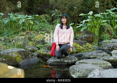 Junge Asiatin in einem japanischen Garten in der Nähe von einem Teich fischen Posing Stockfoto