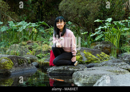 Junge Asiatin in einem japanischen Garten in der Nähe von einem Teich fischen Posing Stockfoto