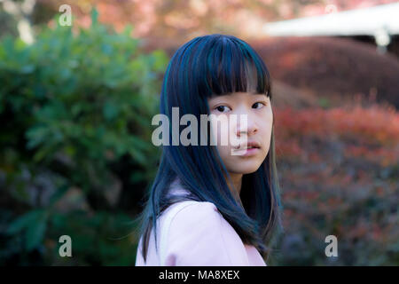 Porträt der schöne junge asiatische Frau mit blauen und grünen Haaren in einem japanischen Garten Stockfoto