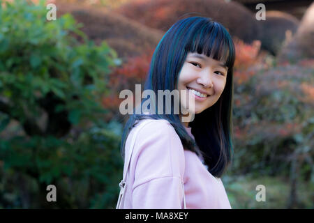 Porträt der schöne junge asiatische Frau mit blauen und grünen Haaren in einem japanischen Garten Stockfoto