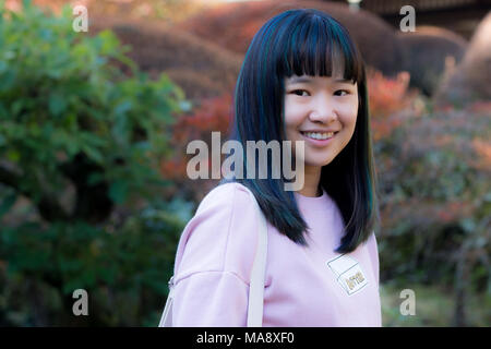 Porträt der schöne junge asiatische Frau mit blauen und grünen Haaren in einem japanischen Garten Stockfoto