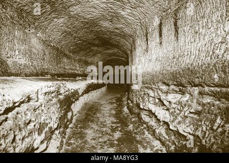 Die alte Sandstein Tunnel, Höhlen abgebaut. Die Höhle. Sandstein Tunnel feuchten Wänden. Trockene Kanal in den felsigen Untergrund geschnitzt. Solarisation Wirkung Stockfoto