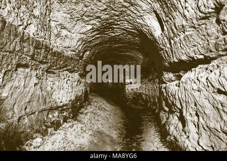 Die alte Sandstein Tunnel, Höhlen abgebaut. Die Höhle. Sandstein Tunnel feuchten Wänden. Trockene Kanal in den felsigen Untergrund geschnitzt. Solarisation Wirkung Stockfoto