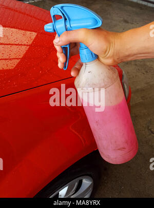 Der Mann spritzt das Auto mit Wachs Stockfoto