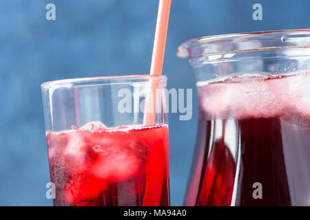 Gesundes Erfrischungsgetränk aus Eis Hibiskus Tee- und roten Beeren und Obst Saft in Krug und hohes Glas mit Stroh. Vitamine Superfoods Detox Hydrat Stockfoto