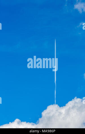 Flugzeug oder kommerzielle Flugzeuge aus den Wolken vertikal hoch direkt fliegen mit kondensstreifen vor blauem Himmel Stockfoto