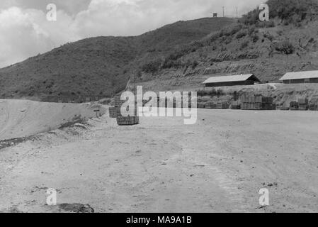 Schwarz-weiß Foto zeigt ein Blick auf die gestapelten Netzteile in einer sandigen Landschaft, mit kasernen Rechts und einen Beobachtungsposten auf einem Hügel im Hintergrund, die in Vietnam während des Vietnam Krieges, 1971 fotografiert. () Stockfoto