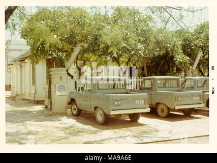 Farbfoto, zeigen drei Ford Pickup Trucks vor einem lattenzaun geparkt, mit Bäumen und einem weißen Haus im Hintergrund, die in Vietnam während des Vietnam Krieges fotografiert (1955-1975), 1968. () Stockfoto