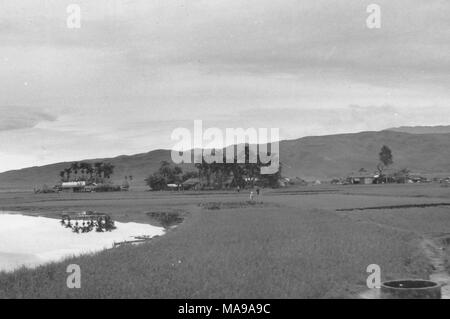 Schwarz-weiß Foto zeigt eine Landschaft, mit einem See und Reisfelder im Vordergrund, Häuser und Bäume im Mittelgrund und einem Hügel im Hintergrund, die in Vietnam während des Vietnam Krieges fotografiert (1955-1975), 1968. () Stockfoto