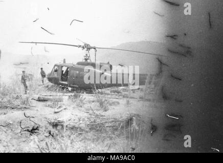 Schwarz-weiß Foto zeigt zwei Männer, anscheinend Ziehen an Seilen in einen Hubschrauber, der auf einem sandigen und felsigen Landschaft angedockt ist beigefügt, die in Vietnam während des Vietnam Krieges fotografiert (1955-1975), 1971. () Stockfoto