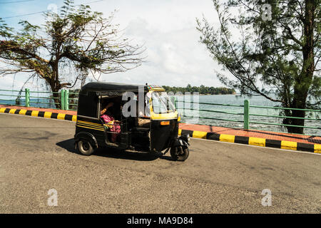 Tuk Tuk Passagiere auf der Straße gegen das Meer. Andaman und Nicobar Inseln, Port Blair. Indien. Januar 12, 2018 Stockfoto