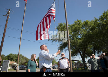 Pastor Frank Pomeroy wirft eine amerikanische Flagge auf der Website von einem Shooting, 26 leben außerhalb der First Baptist Church von Sutherland Springs während einer Presseveranstaltung fünf Monate nach dem Massaker behauptete. Us-Senator John Cornyn steht auf der rechten Seite. Stockfoto