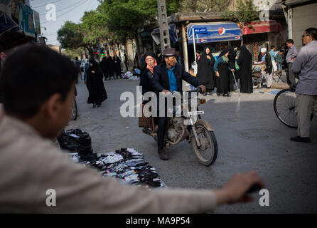 Mashhad, Iran. 30 Mär, 2018. Ein Afghanischer Flüchtling reitet ein Motorrad mit seiner Frau am Stadtrand von Mashhad, Iran, 30. März 2018. Seit 2002 sind rund 4,3 Millionen afghanische Flüchtlinge haben freiwillig in Afghanistan im Rahmen des trilateralen Rahmen und UNHCR zurückgekehrt - erleichtert die freiwillige Rückführung Programm, entsprechend dem UNHCR. Credit: Ahmad Halabisaz/Xinhua/Alamy leben Nachrichten Stockfoto