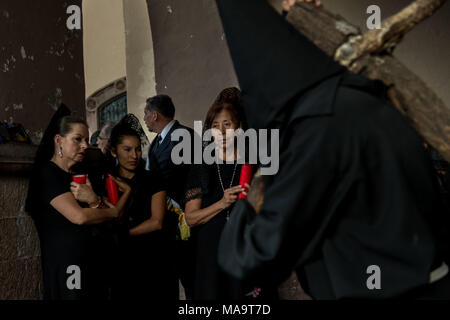 Querétaro, Mexiko, 31. Feb 2018. Vermummte Büßer tragen Holzkreuze, wie sie die Prozession der Stille durch die Straßen am Karfreitag während der Heiligen Woche März 30, 2018 in Querétaro, Mexiko beginnen. Die Büßer, bekannt als Nazarener, tragen die schwere Kreuze und Ketten ziehen an einem vierstündigen März in Erinnerung an die Passion Christi. Credit: Planetpix/Alamy leben Nachrichten Stockfoto