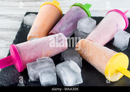 Hausgemachte Eiscreme von Beeren. Kalten Sommer Dessert aus gefrorenen Aprikosenpülpe, Pfirsiche, Johannisbeeren, Erdbeeren, Blaubeeren mit Eis auf schwarze Platte auf Stockfoto