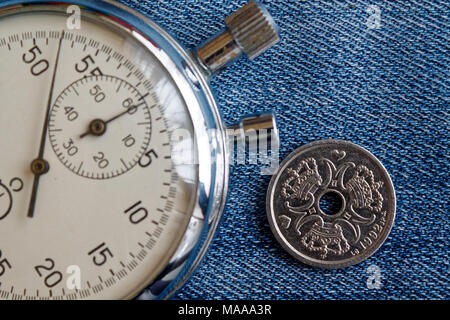 Dänemark Münze mit einer Stückelung von einer Krone (Krone) (Rückseite) und die Stoppuhr auf Old Blue Jeans Hintergrund - Hintergrund Stockfoto
