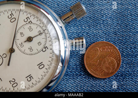 Euro Münze mit einer Stückelung von 2 Cent und die Stoppuhr auf abgenutzten Jeans Hintergrund - Hintergrund Stockfoto