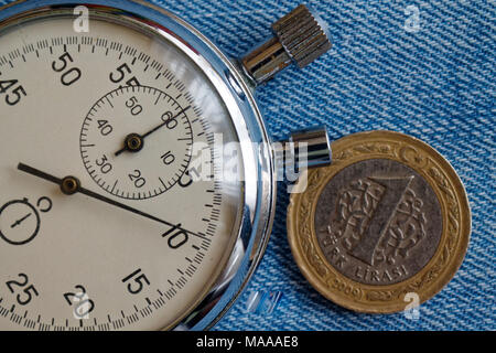 Türkische Münze mit einer Stückelung von 1 Lira und Stoppuhr auf dem alten blauen Jeans Hintergrund - Hintergrund Stockfoto