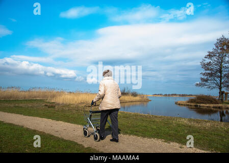 Ältere Frau, die mit Rollator nach draußen geht, Holland Stockfoto