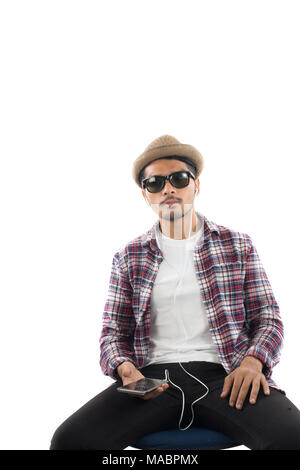 Junge hipster Mann in Ohrhörer holding Smartphone auf dem weißen Hintergrund. Stockfoto