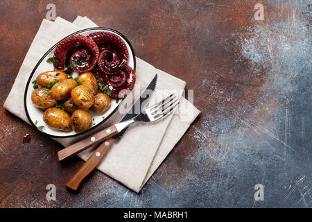 Gegrillter Tintenfisch mit kleinen Kartoffeln mit Kräutern und Gewürzen. Ansicht von oben mit Platz für Ihren Text Stockfoto