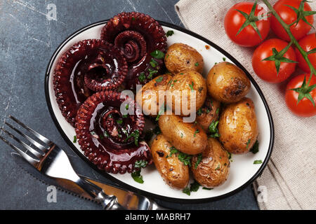 Gegrillter Tintenfisch mit kleinen Kartoffeln mit Kräutern und Gewürzen. Ansicht von oben Stockfoto