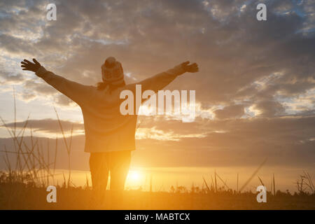 Silhouette einer Frau, die auf dem Feld während des Sonnenuntergangs. Stockfoto