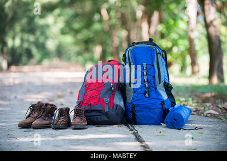 Rucksack und Schuhe backpackers Rest auf der Straße, während sie wandern. Stockfoto