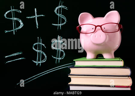 Rosa Sparschwein mit Brille auf Bücher neben einer Tafel mit einfachen Geld Mathematik stehen.  Scharfe Fokussierung auf das Sparschwein. Stockfoto