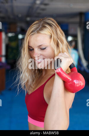 Junge blonde Frau mit kettlebell im Fitnessraum, Gymnastik Stockfoto