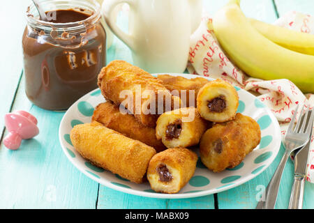 Hausgemachte Dessert frittierte Bananen frittierte mit Schokolade auf einem hölzernen Tisch in einem rustikalen Stil gefüllt. Stockfoto