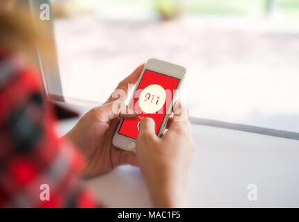 Frau mit einem Smartphone wählen Sie die Notrufnummer auf dem Bildschirm. Grafiken auf dem Bildschirm. Stockfoto