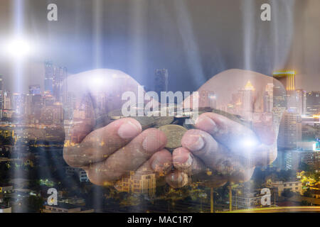 Doppelbelichtung Geschäftsmann holding Münze in der Hand mit Stadtbild bei Nacht Hintergrund. Stockfoto