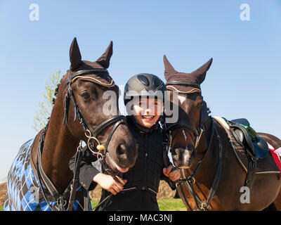 Porträt der Glückliche junge Mädchen nach dem Gewinn der Springreiter Wettbewerb mit ihren beiden Pferden Stockfoto