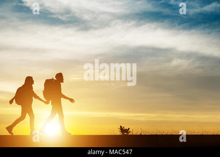 Paar wandern helfen, Teamwork und Vertrauen silhouette Wandern während des Sonnenuntergangs. Mann und Frau, Wanderer, die sich gegenseitig helfen, schöne Nacht Landschaft. Stockfoto