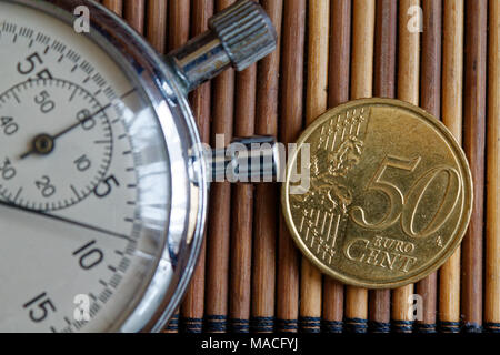 Stoppuhr und Münze mit einer Stückelung von fünfzig Cent auf hölzernen Tisch Hintergrund Stockfoto