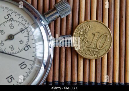 Stoppuhr und Münze mit einer Stückelung von 10 Euro Cent auf hölzernen Tisch Hintergrund Stockfoto