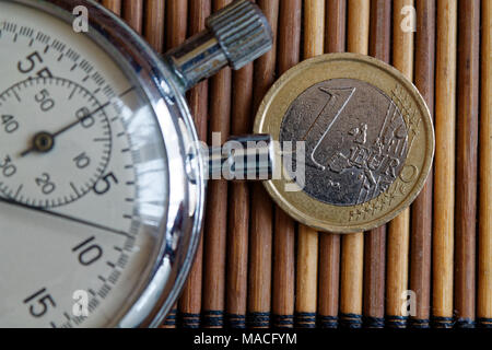 Stoppuhr und die Münze mit einem Nennwert von einem Euro auf hölzernen Tisch Hintergrund Stockfoto
