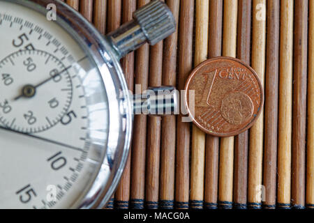Stoppuhr und Münze mit einer Stückelung von 1 Euro Cent auf hölzernen Tisch Hintergrund Stockfoto