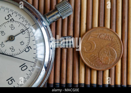 Stoppuhr und Münze mit einer Stückelung von fünf Cent auf hölzernen Tisch Hintergrund Stockfoto