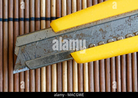 Die gelbe feststehenden Messer auf hölzernen Hintergrund isoliert Stockfoto