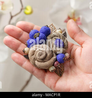 Kleine handgefertigte Brosche in Form von zwei beige Blumen auf der Handfläche eine Frau close-up Stockfoto