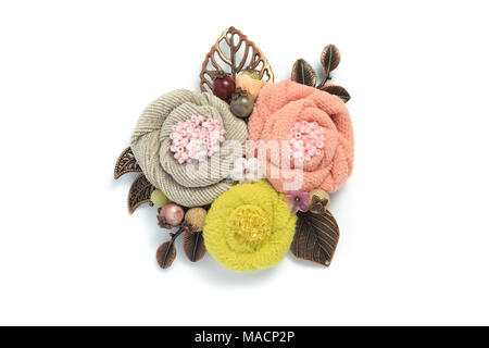 Brosche Handarbeit aus einem Stoff, bestehend aus drei Blumen grau, rosa und gelben Farben Stockfoto