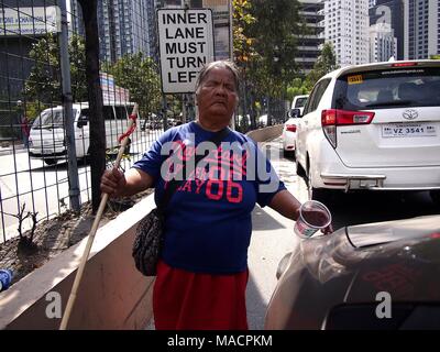 PASIG CITY, Philippinen - 20. MÄRZ 2018: einem blinden Bettler bittet um Geld von vorbeifahrenden Fahrzeuge entlang einer befahrenen Straße. Stockfoto