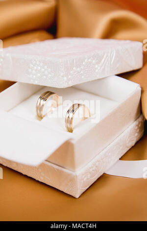 Schöne Hochzeit Ringe in weiß Luxus Box auf gelbe Seide Stockfoto