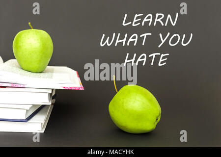 Zwei grüne Äpfel und offenen Bücher auf grauem Hintergrund mit Text erfahren Sie, was Sie hassen. Konzept Zurück zur Schule Stockfoto