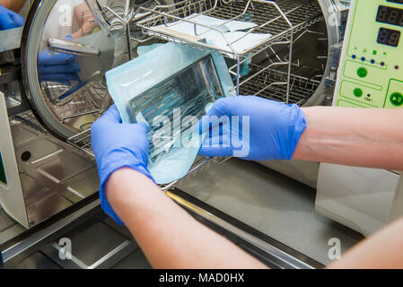 Nahaufnahme der Zahnarzt assistant Hände gelangen, Sterilisierung medizinischer Instrumente von Autoklaven in der Zahnarztpraxis. Selektiver Fokus Stockfoto