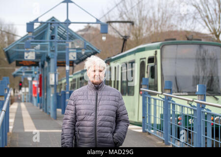 Ältere Frau mit grauen Haaren an der Straßenbahnhaltestelle Stockfoto