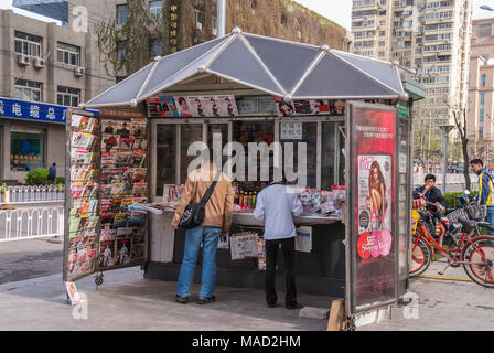 Peking, China - 26. April 2010: News stand, Kiosk, mit vielen bunten Zeitschriften auf Anzeige hat zwei Kunden vor. Street Scene mit Street, Stockfoto